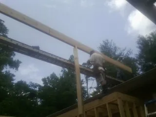 Carpenter setting a ridge beam over a new addition frame — Ice Dam Removal by Roofing Brothers in Towanda