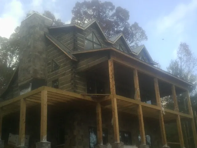 Stone chimney and dormers on a large log home with a timber porch in Towanda