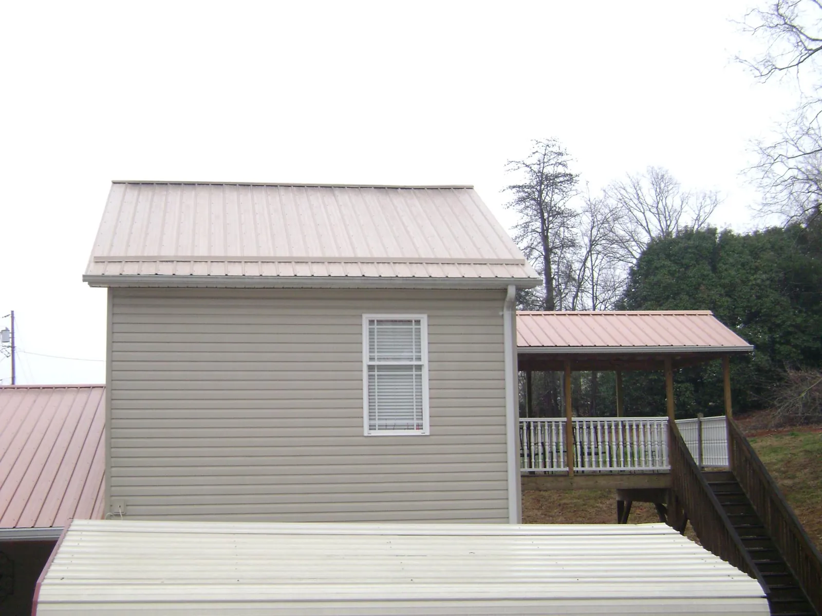 Tan metal roofs on a two story addition and attached porch, from a Roof Replacement job in Towanda